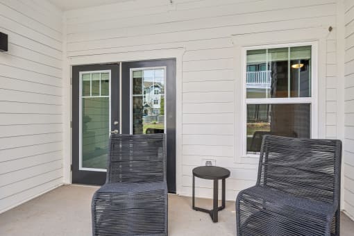 a front porch with two chairs and a small table