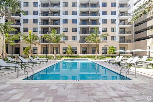 A large swimming pool in front of a multi-story apartment building.