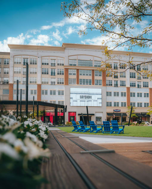 a large white building with blue chairs in front of it at The Bayshore Place Apartments in Glendale, WI