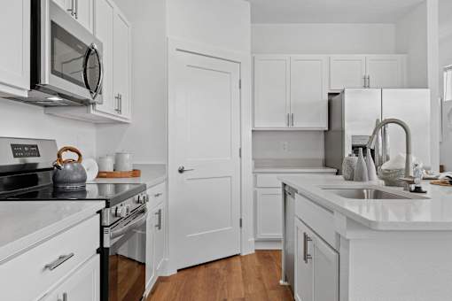 A white kitchen with a stove, oven, microwave, and refrigerator.