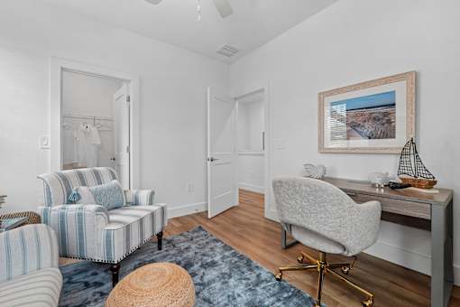 A room with a chair, a desk, and a painting on the wall.