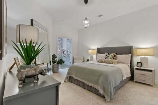 A bedroom with a large bed and a piggy bank on the dresser.