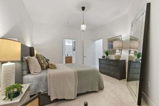 A bedroom with a bed, dresser, and mirror.