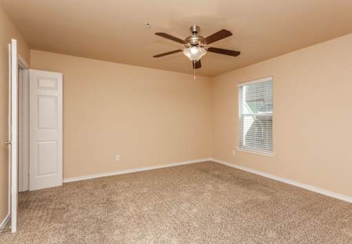 A room with a ceiling fan and carpeted floor.