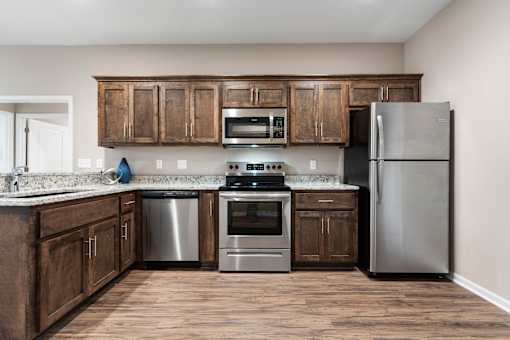 Senior Apartments Near Belton, MO for Rent - Traditions Villas 55+ - Kitchen with a High Ceiling, Vinyl Plank Flooring, Custom Cabinetry, Granite Countertops, and Stainless Steel Appliances.