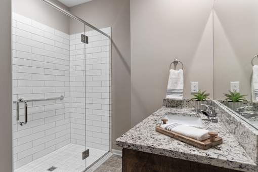 A bathroom with a marble counter top and a walk in shower.