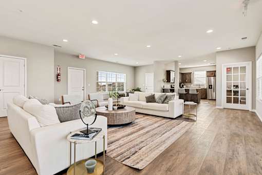 A spacious living room with white furniture and a wooden floor.