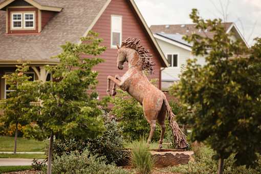 A wooden horse statue stands in front of a house.