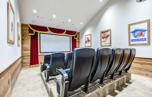 A row of black chairs are lined up in front of a screen in a room with wooden walls.