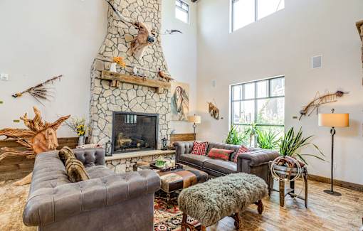 A living room with a stone fireplace and a grey couch.