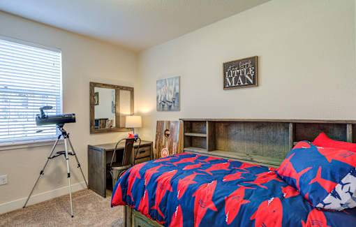 A bedroom with a bed covered in a blue and red fish print bedspread.