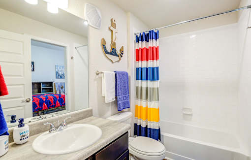 A bathroom with a white sink and a shower curtain with red, white and blue stripes.