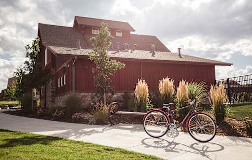 A bicycle is parked in front of a red barn.