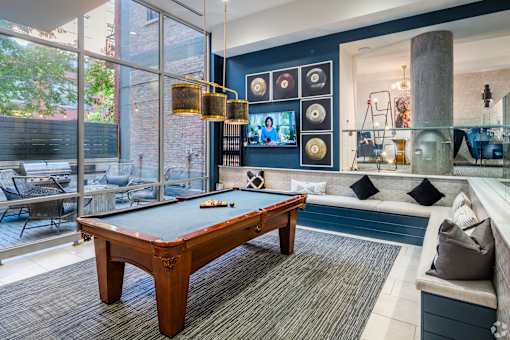 A pool table is in the middle of a room with a couch and a TV.