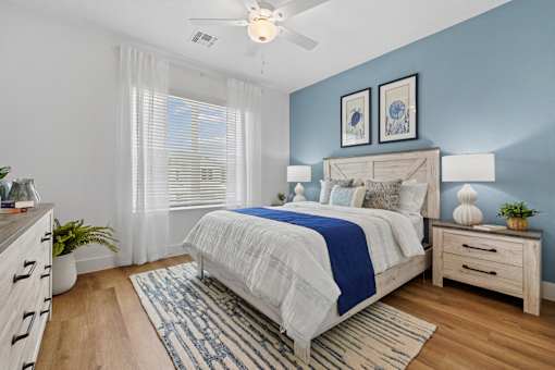 A bedroom with a bed, nightstand, and a ceiling fan.