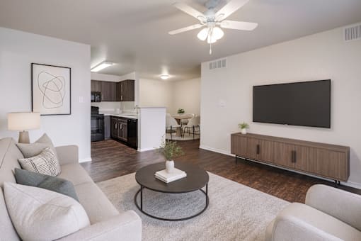 A living room with a grey couch, a coffee table, and a flat screen TV mounted on the wall.