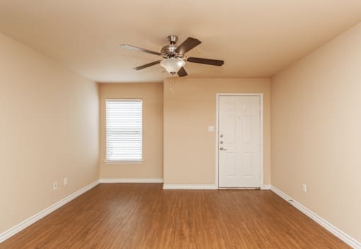 A room with a ceiling fan and a door.