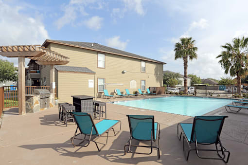 A pool area with chairs and a building in the background.