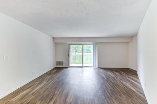 an empty living room with a sliding glass door leading to a patio