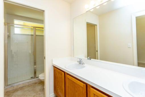 Unfurnished apartment bathroom with oak cabinets and double sinks