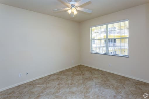 Unfurnished bedroom with carpeting, ceiling fan and window