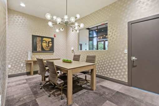 A conference room with a table, chairs, and a painting on the wall.