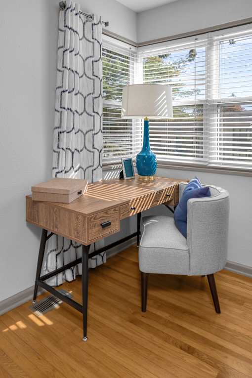 A wooden desk with a chair and a lamp on it.