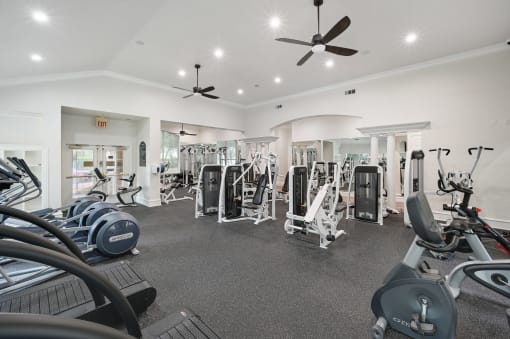 a gym with weights and cardio machines and ceiling fans