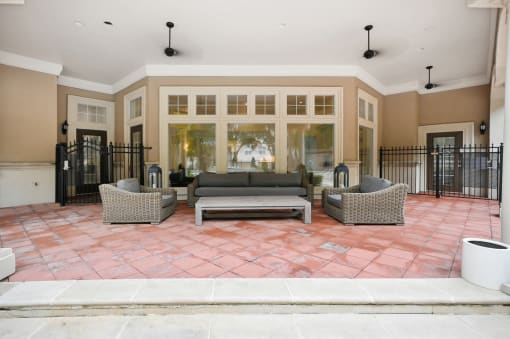 a patio with couches and chairs in front of a building