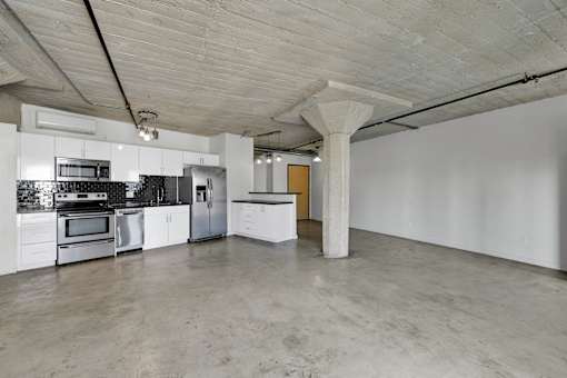 A spacious kitchen with a concrete floor and ceiling.