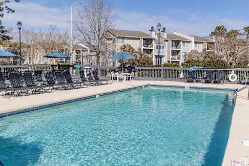 A large swimming pool with a row of chairs and umbrellas.