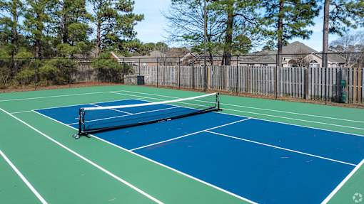 A tennis court with a net and a green and blue surface.