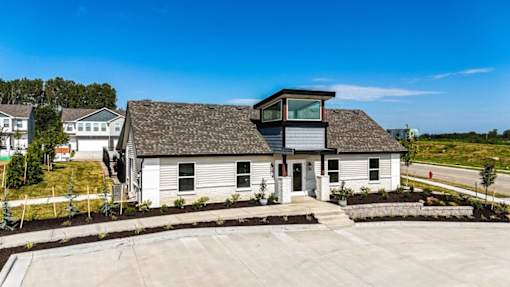 A white building with a grey roof and a small porch.