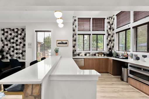 A kitchen with a white counter and black chairs.