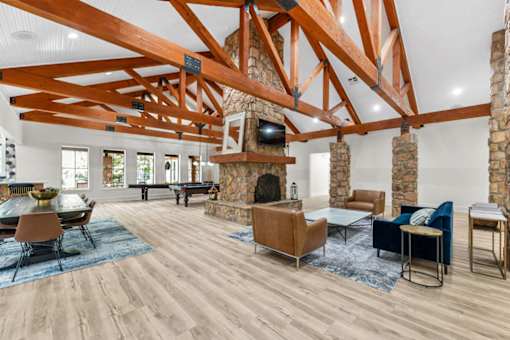A living room with a stone fireplace and wooden beams.