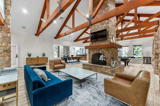 A living room with a stone fireplace and a blue couch.