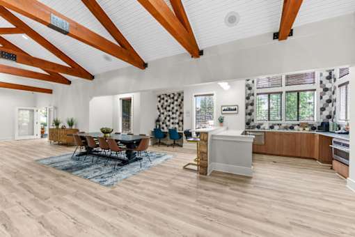 A spacious clubhouse and kitchen area with wooden floors and ceiling beams.
