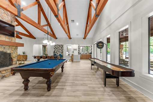 Pool table inside the clubhouse with a wooden floor and a stone fireplace.
