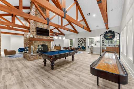 A pool table is in the middle of a room with a fireplace and wooden beams.