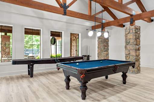 A pool table in a room with wooden floors and a stone pillar.