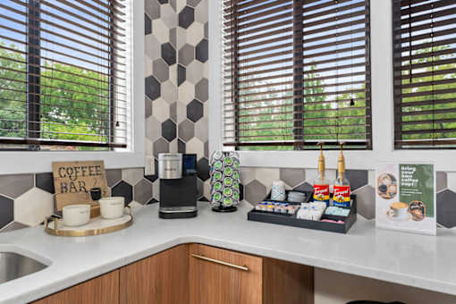 A coffee bar with a coffee machine and cups on a counter.