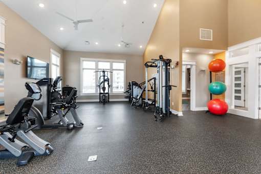 A gym with a variety of equipment including treadmills, elliptical machines, and a television.