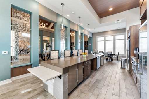 One Bedroom Luxury Apartments in Shawnee, KS - Bonavia Luxury Apartments - Clubhouse Kitchen with Stainless Steel Appliances, Expansive Island with Seating, and Pendant Lights.