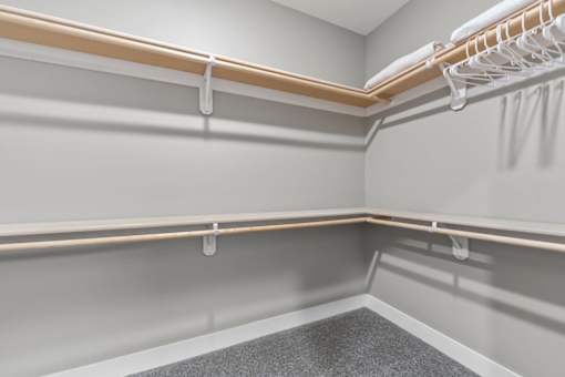 1 Bedroom Luxury Apartments in Shawnee, KS - Bonavia Luxury Apartments - Spacious Closet with Carpeting, Hanging Racks, and Generous Shelf Space.