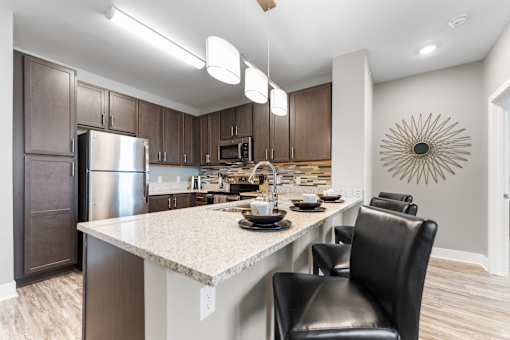 A modern kitchen with a large island and black chairs.
