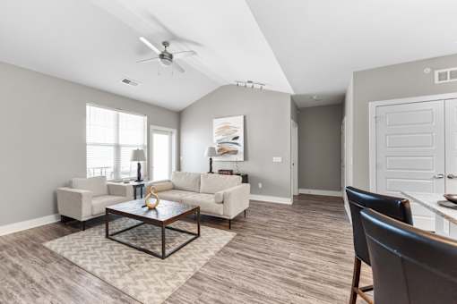 A living room with a ceiling fan and a rug on the floor.