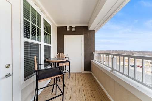 A balcony with a table and chairs overlooking a body of water.