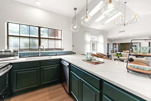 A kitchen with green cabinets and a white countertop.
