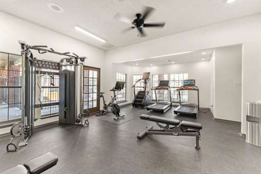 A spacious gym with a variety of equipment including treadmills, stationary bikes, and weight machines.