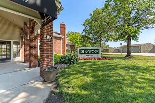 A sign for the Silverwood Apartment Homes is in front of a brick building.